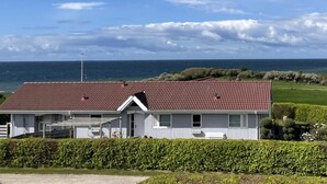 En hvid bygning med rødt tag, beliggende nær vandet.