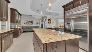 Une cuisine moderne dotée de plans de travail en granit, d’appareils électroménagers en acier inoxydable et de luminaires suspendus.
