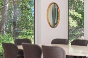 A conference room with a large window, a mirror, and a table with chairs.