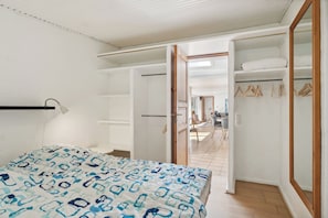 Un dormitorio con cama, armario y puerta abierta que da a un comedor.