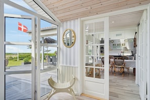 A room with a large window, a wooden ceiling, and a dining area with chairs and a table.