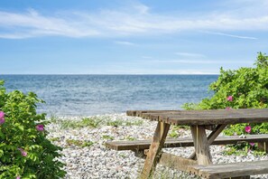 Een houten picknicktafel aan een rotsachtige kust met uitzicht op de zee.