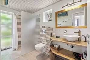 Un baño con inodoro, lavamanos, espejo y ducha.