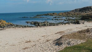 Une plage avec des affleurements rocheux et une eau d’un bleu cristallin.
