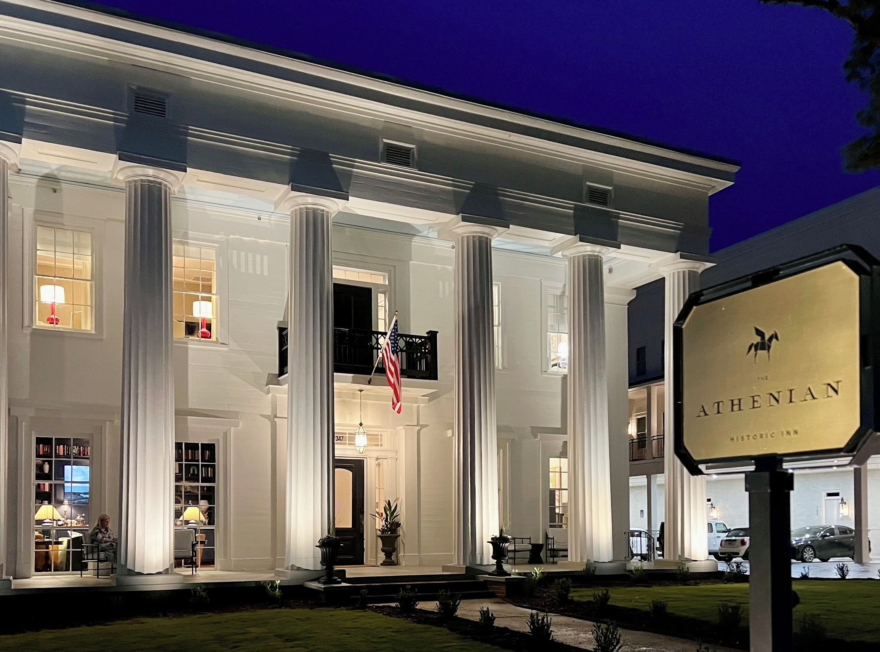 A historic inn with a grand entrance, large columns, and a flag.