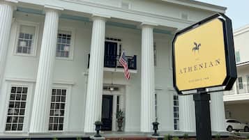 A historic inn with a white facade, large columns, and an American flag.