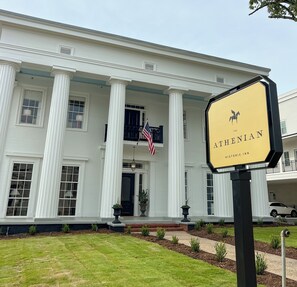 Een historisch herberg met een witte gevel, brede zuilen en een Amerikaanse vlag.