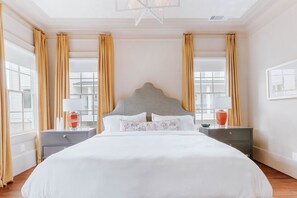 Habitación de hotel con una cama grande, dos mesitas de noche y un ventanal con cortinas.