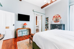 A bedroom with a bed, a TV, a bookshelf, and a fireplace.
