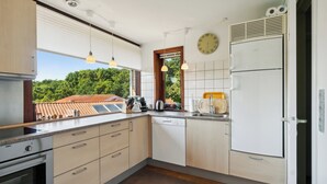 Eine moderne Küche mit eingebauten Geräten, einem Fenster mit Blick auf Grünflächen und Pendelleuchten.