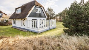 A house with a thatched roof, white exterior walls, and a fenced garden area.