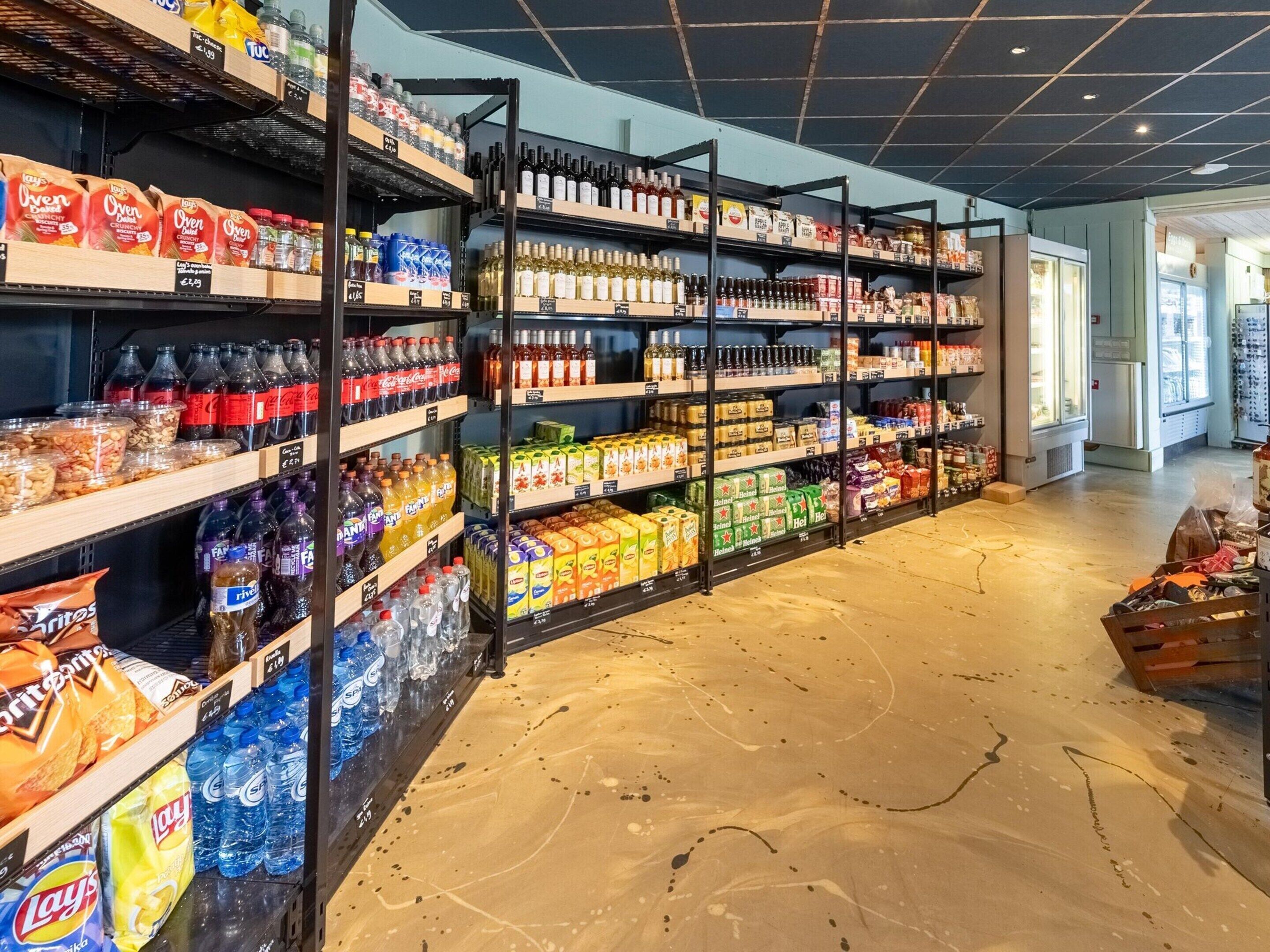 Un rayon d’épicerie où les étagères sont remplies de collations, de boissons et d’articles ménagers.