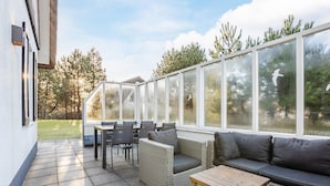 A covered patio area with outdoor furniture, including a sofa, chairs, and a table.