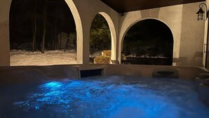 A hot tub with blue lighting, surrounded by arched structures and outdoor seating.