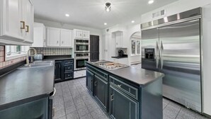 A modern kitchen with white cabinets, stainless steel appliances, and a central island.