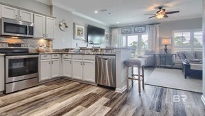 Une cuisine moderne dotée d’appareils électroménagers en acier inoxydable, de meubles blancs et d’un plancher en bois.
