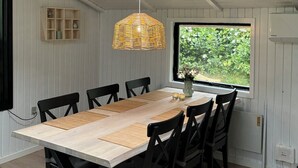 A dining area with a skylight, a hanging light fixture, and a window with a view of greenery. - Cozy cottage with a wilderness hot tub (Sydals)
