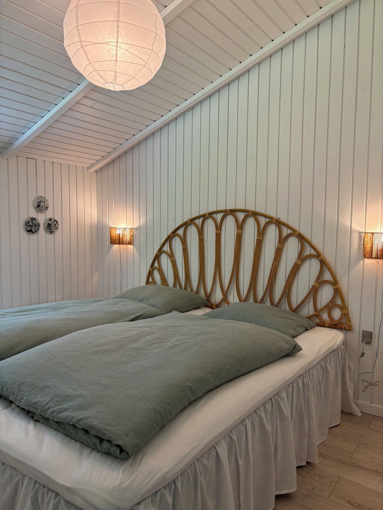 Une chambre à coucher avec un lit, un luminaire suspendu et des lampes fixées au mur.