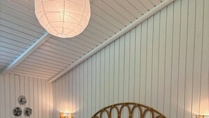 A bedroom with a bed, a hanging light fixture, and wall-mounted lamps. - Cozy cottage with a wilderness hot tub (Sydals)