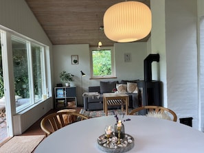 En hyggelig stue med pejs, et spisebord med stearinlys og et stort vindue.