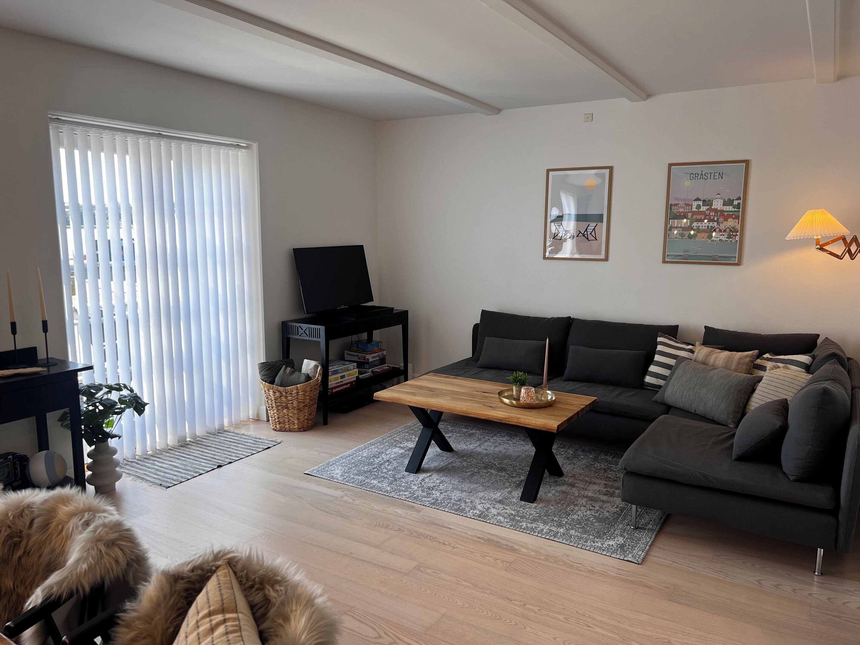 A modern living room with a sofa, a coffee table, a television on a stand, a lamp, and a framed picture on the wall.