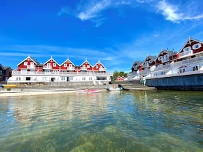 A waterfront hotel with red and white buildings, a dock with boats, and clear water. - Luxury holiday home with sea view (Gråsten)