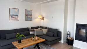 A modern living room with a grey sofa, a wooden coffee table, and a fireplace. - Luxury holiday home with sea view (Gråsten)