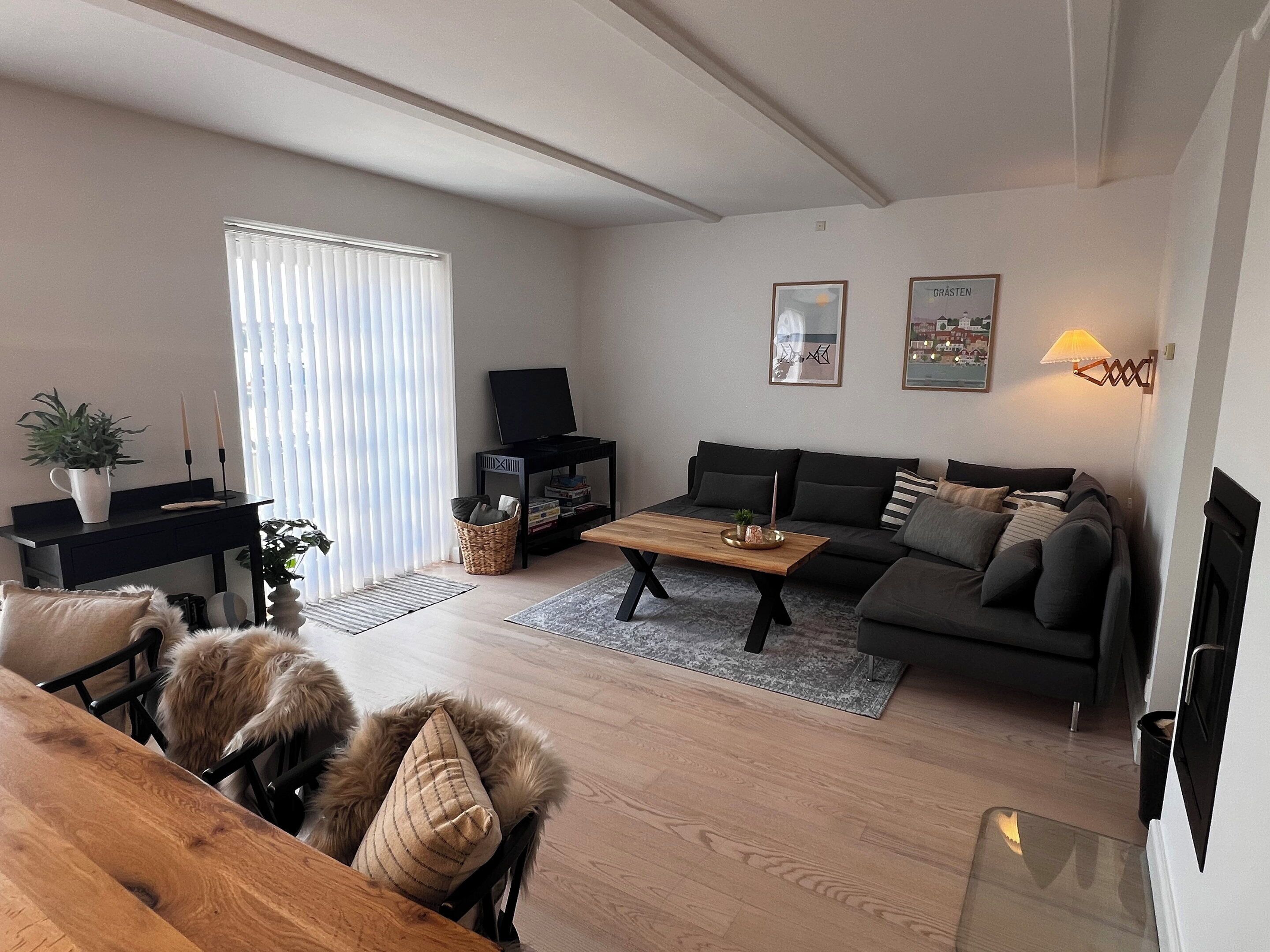 Un salon moderne avec un canapé, une table basse, un téléviseur et une cheminée.