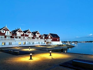 A waterfront hotel with multiple red and white buildings, a dock, and a calm body of water. - Luxury holiday home with sea view (Gråsten)