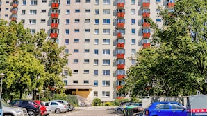 A multi-story residential building with balconies, a parking area, and trees. - Winogrady Stylish Apartment (Poznań)