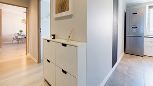A modern kitchen with a stainless steel refrigerator, a white cabinet with black handles, and a framed artwork on the wall. - Winogrady Stylish Apartment (Poznań)