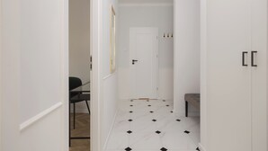 A hallway with a white door, a bench, and a framed picture on the wall. - Chmielna Green Apartment (Warszawa)