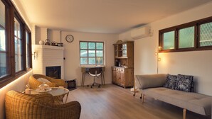 Una sala acogedora con chimenea, muebles de mimbre, un sofá y un comedor.