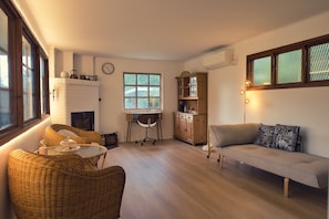 A cozy living room with a fireplace, wicker furniture, a sofa, and a dining area.