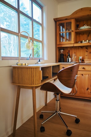Un bureau en bois avec une chaise, une fenĂȘtre et un coin cuisine avec des placards.