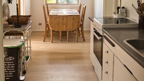 Una cocina con muebles de madera, una mesa de comedor y un ventanal con luz natural.