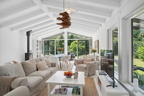 Een ruime woonkamer met een hoge plafond, grote ramen en een moderne open haard.