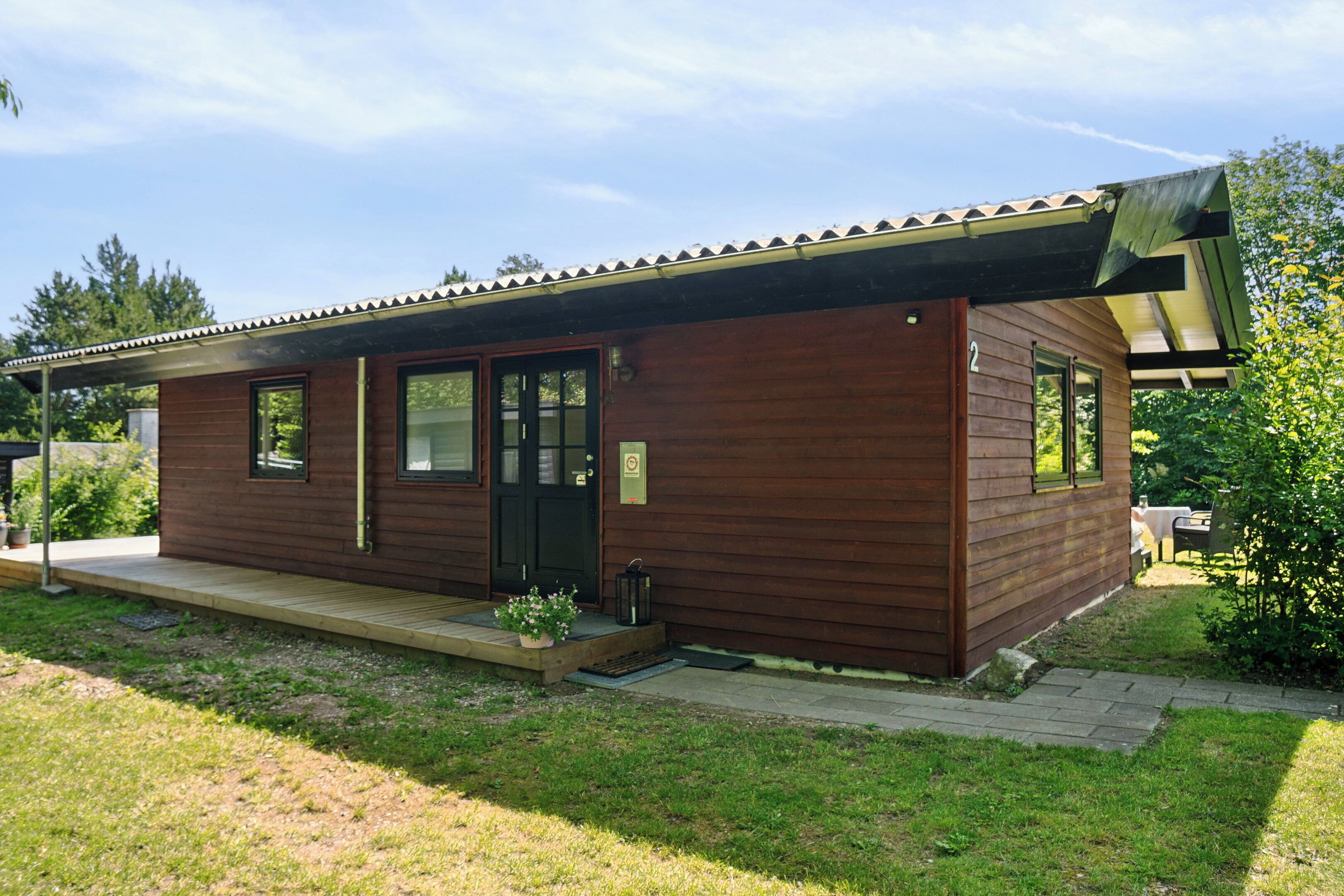 A wooden cabin with a porch, a door, and windows.