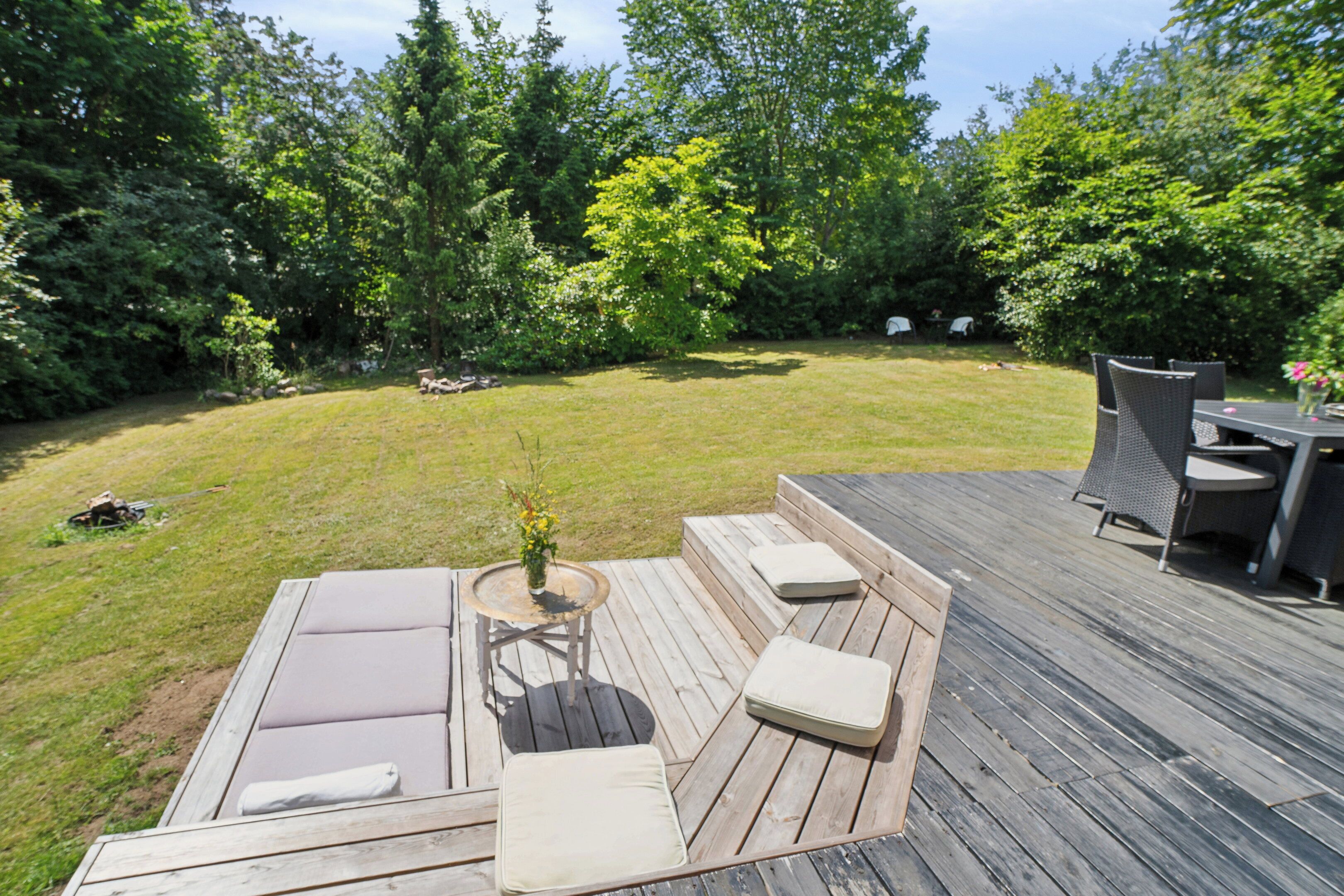 A deck with outdoor seating and a small table with a vase of flowers.