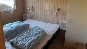 A bedroom with a bed, two bedside lamps, a window, and a small white nightstand. - Holiday home near Hvalpsund (Farsø)