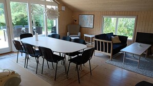 A spacious room with a large dining table, black chairs, a sofa, a TV, and a map on the wall. - Holiday home near Hvalpsund (Farsø)