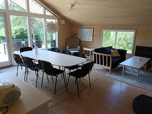 Tilava huone, jossa on suuri ruokapöytä, mustat tuolit, sohva, televisio ja seinällä oleva kartta.