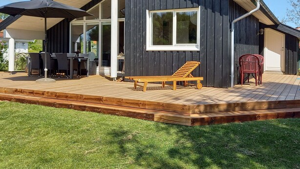 A modern house with a deck, a dining area, and a lounge chair. - Holiday home near Hvalpsund (Farsø)