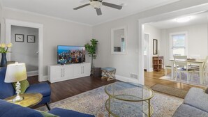 Una sala de estar con televisión, sofá, mesa de centro y un comedor con mesa y sillas.