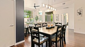 A dining area with a wooden table and chairs, a ceiling fan, and large windows. - The Cozy Corner Retreat 15 min Walk to Old Town (Fort Collins)