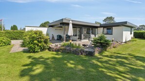 A modern house with a patio, outdoor seating, and a well-maintained garden. - Atmospheric summer cottage at Hejlsminde (Hejls)