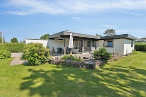 A modern house with a patio, outdoor seating, and a well-maintained garden.