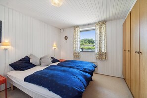 A bedroom with two beds, a wardrobe, a window with curtains, and wall-mounted lights.
