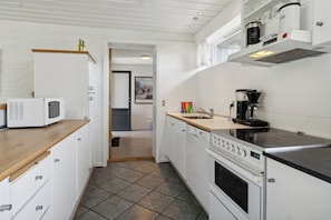A modern kitchen with white cabinetry, a microwave, a coffee maker, and a stove.