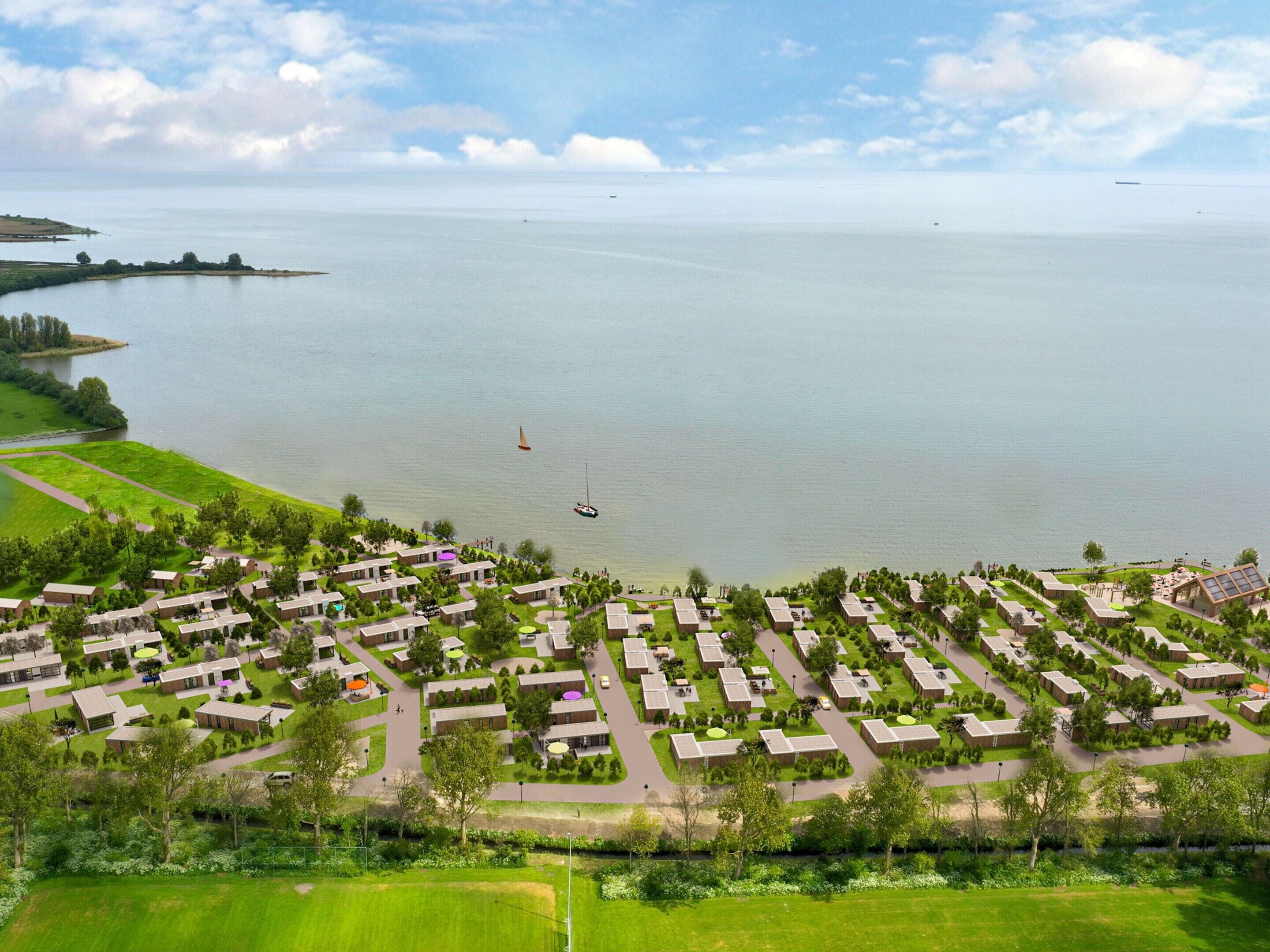 An aerial view of a coastal resort with multiple bungalow-style accommodations, a marina, and a large body of water.